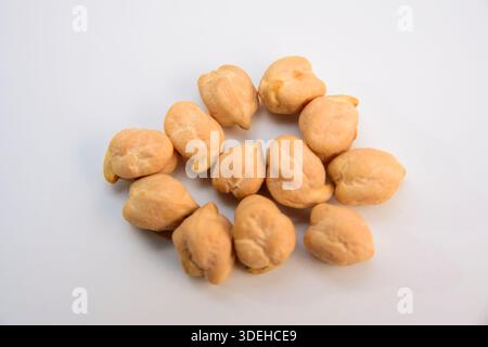 Makronaht einiger getrockneter Kichererbsen auf weißem Hintergrund. Texturdetails des Rohleguminoseninhalts. Stockfoto