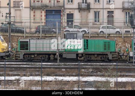 Nancy, Frankreich - Blick auf einen grauen und grünen schweren Jäger BB 60000, der den Bahnhof Nancy überquert, mit Gebäuden und Autos im Hintergrund. Stockfoto