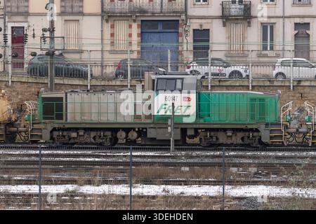 Nancy, Frankreich - Blick auf einen grauen und grünen schweren Jäger BB 60000, der den Bahnhof Nancy überquert, mit Gebäuden und Autos im Hintergrund. Stockfoto