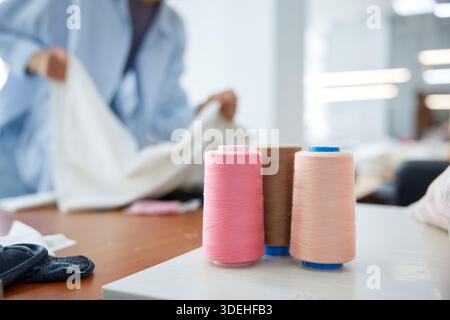 Handwerker arrangieren in hell beleuchtetem Nähstudio mit Sorgfalt Textilien und Accessoires Stockfoto