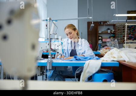 Junge Handwerker mit Fokus auf präzise Stiche in moderner Werkstatt Stockfoto