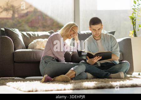 Glückliches junges Paar, das zu Hause zusammen ein Buch ansieht Stockfoto