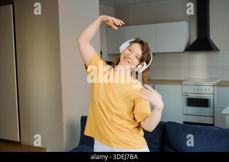 Frau, die Musik genießt und frei tanzt, zu Hause in ihrer Wohnung Stockfoto