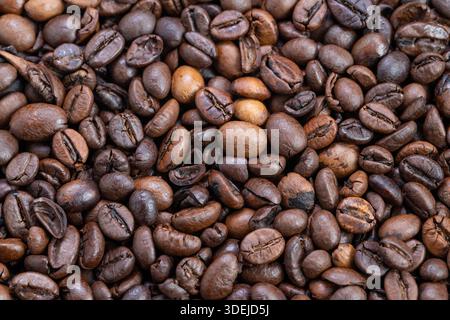 Close-up-Kaffeebohnen mit Kontrast zwischen hellen und dunklen Rösten, goldenen Highlights und ausgewogenen Tönen, die an Schröpfprobe und Geschmack erinnern Stockfoto