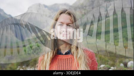 Stehende Frau mit orangefarbenem Pullover und Hemd im Bergtal mit transparentem Flügelüberzug Stockfoto