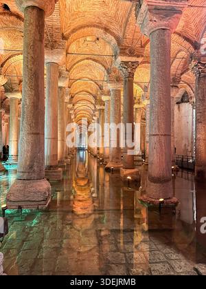 Alte Marmorsäulen der Basilika-Zisterne mit Wasserreflexionen und warmer atmosphärischer Beleuchtung in Istanbul. Stockfoto