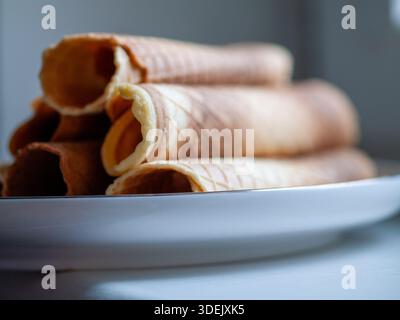 Leere gerollte Wafer-Kegel auf einer weißen Platte, Nahaufnahme mit geringer Schärfentiefe. Stockfoto