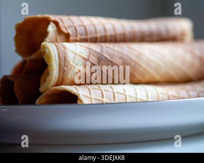 Gerollte Waffelkegel in einer Reihe, Nahaufnahme leerer Waffeleiskegel. Stockfoto