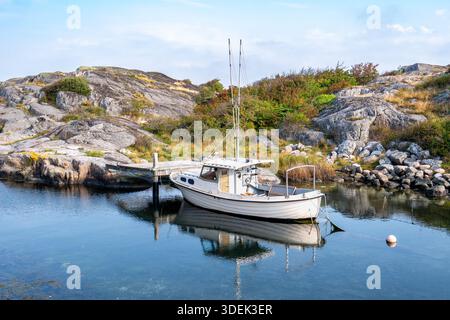 Kleines Fischerboot, das am Holzsteg an der felsigen Küste der Insel Hönö, dem Archipel Öckerö, der Westküste Schwedens vor Anker liegt Stockfoto