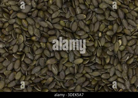 Geschälte grüne Kürbiskerne verstreut, zeigen Textur und gesunde Ernährung. Vollbild-Makroaufnahme. Stockfoto