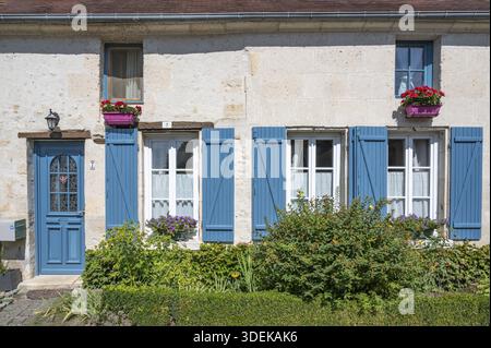 Nahaufnahme einer traditionellen Hausfassade in Saint-Jean-aux-Bois mit hellen Kalksteinwänden, markanten blauen Fensterläden (Volets) und einem passenden blu-ray Stockfoto