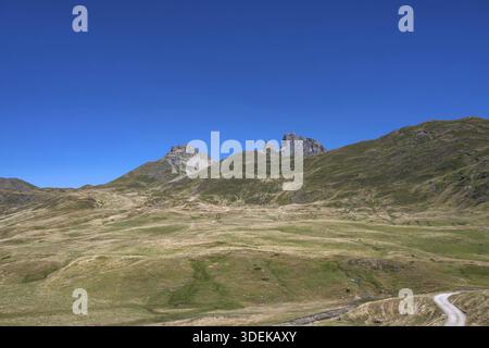 Der Blick auf die weiten, sommerlich braun-grünen Hochwiesen im Cirque d'Aneu zeigt die unverwechselbare Silhouette des PIC du Midi d'Ossau im Hinterland Stockfoto