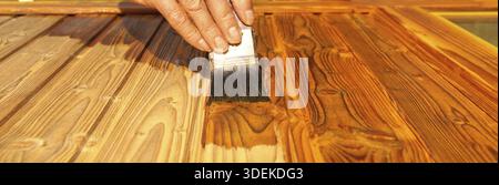 Lasurer. Holzmalerei im Freien. Hand von Handyman, die eine Holztür lackiert. Konzept der Renovierungsarbeiten, Zimmermannsdetails mit Holzarbeiten. Maler p Stockfoto
