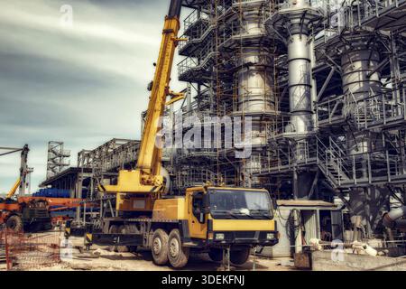 Auf der Baustelle einer Ölraffinerie steht ein großer gelber Autokran Stockfoto