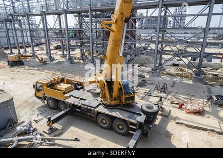 Auf der Baustelle einer Ölraffinerie steht ein großer gelber Autokran Stockfoto