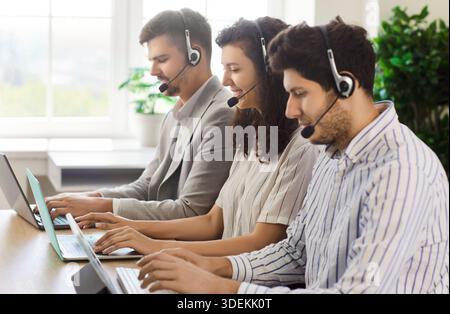 Callcenter-Agenten mit Headsets arbeiten mit Laptops am Schreibtisch und unterstützen Kunden Stockfoto