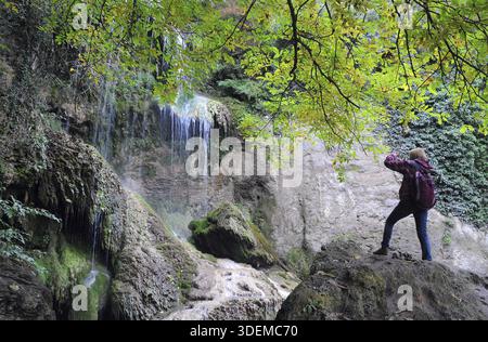 Weiße Frau fotografiert den Wasserfall im Herbst Stockfoto