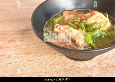 Scharfes Hähnchenfleisch mit Zwiebeln und Tomaten in tom-Yum-Suppe auf einer Schüssel Stockfoto