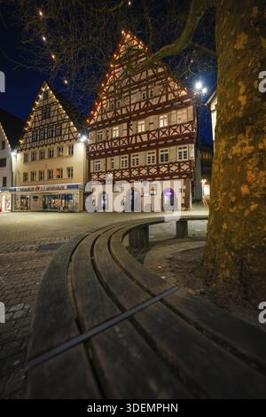 Wunderschöne Fachwerkhäuser erstrahlen nachts unter Feenlichtern, die von einer gebogenen Holzbank erfasst werden, Nagold, Calw Bezirk, Schwarzwald, Deutschland Stockfoto