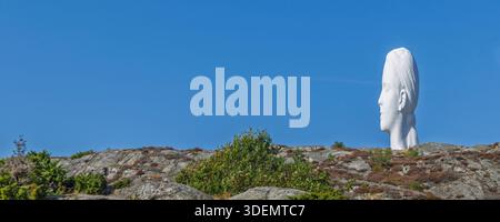 Tjorn, Schweden - 3. September 2025: Ein großer weißer Skulpturenkopf an der Skulptur i Pilane erhebt sich über einem felsigen Hügel, der von Grün umrahmt wird Stockfoto
