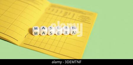 Masern dargestellt als Holzwürfel auf dem Hintergrund des deutschen Impfzertifikats, die Impfungen gegen Masern symbolisieren, Panoramabilder Stockfoto