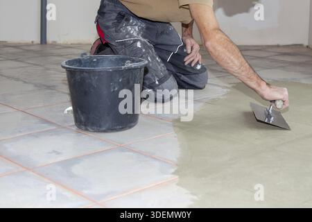 Bauarbeiter Nivelliermasse mit Spachtelmesser. Renovierung, Boden Nivellierung Estrich, Massenverteilung. Vorbereitung für einen gleichmäßigen Boden zum Einbau Stockfoto