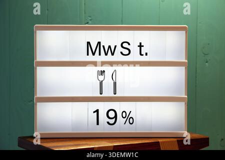 Mwst 19% Nachricht auf weißem Schild zu Hause auf einem grünen Regal. Erhöhung der Mehrwertsteuer in der Gastronomie. Meldung auf weißem Schild. Konzept der Erhöhung des Mehrwertsteuersatzes Stockfoto