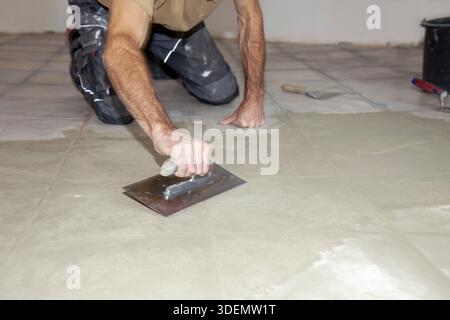 Bauarbeiter Nivelliermasse mit Spachtelmesser. Renovierung, Boden Nivellierung Estrich, Massenverteilung. Vorbereitung für einen gleichmäßigen Boden zum Einbau Stockfoto