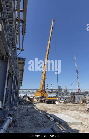 Auf der Baustelle des neuen Werks steht ein großer gelber Lkw-Kran einsatzbereit Stockfoto