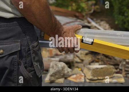 Rückansicht des Arbeiters, der eine Wasserwaage und ein Lineal in der Hand hält Stockfoto