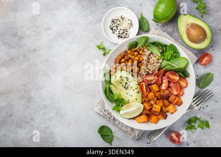 Gesunde vegane Mittagsschale. Avocado, Quinoa, Süßkartoffeln, Tomaten, Spinat und Kichererbsen Gemüsesalat. Draufsicht Stockfoto