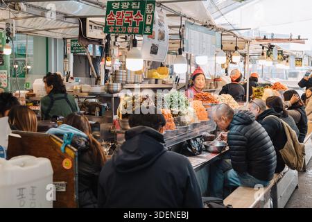 Seoul, 01. Januar 2025: Gäste essen an einem geschäftigen Imbissstand auf dem Gwangjang Market, einem beliebten Touristenziel Stockfoto