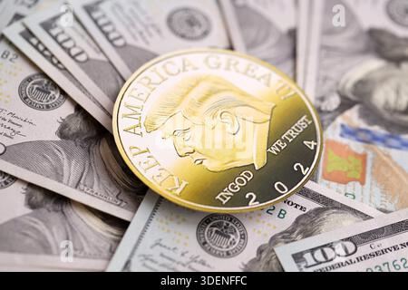 KIEW, UKRAINE - 13. DEZEMBER 2025 Trump Goldmünze auf großen Mengen von US-Dollar-Banknoten Stockfoto