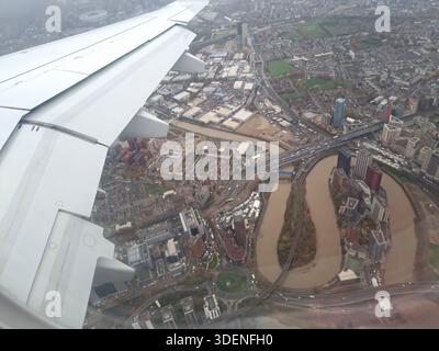 LONDON, VEREINIGTES KÖNIGREICH - 10. NOVEMBER 2025: Eine Luftaufnahme mit dem Bow Creek und dem Fluss Lea bei einer Abfahrt vom Flughafen London City bei regnerischem, grauem Wetter. Das Stadtbild/die Landschaft umfasst den Bow Creek Ecological Park und den Limmo Peninsula Ecological Park, der von der East India Dock Road und dem Newham Way durchschnitten wird. Die Station Canning Town ist auf der rechten Seite des Rahmens zu sehen. Das Foto wurde von einem Embraer 190-Flugzeug aufgenommen. Stockfoto