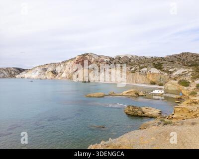 Blick aus der Vogelperspektive auf den ruhigen Strand von Firiplaka, wo türkisfarbenes Wasser auf die dramatischen Klippen und Felsvorsprünge trifft, Firiplaka Beach, Milos, Griechenland. Stockfoto