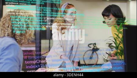 Leving Lead Woman in blassem Blazer, die das Team bei der Überprüfung von Laptop, Papieren und Code-Overlay im Büro anleitet Stockfoto