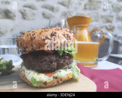 Saftiges Rindfleisch, frischer Salat und Soße, auf einem gesunden Mehrkornbrötchen mit Bier Stockfoto
