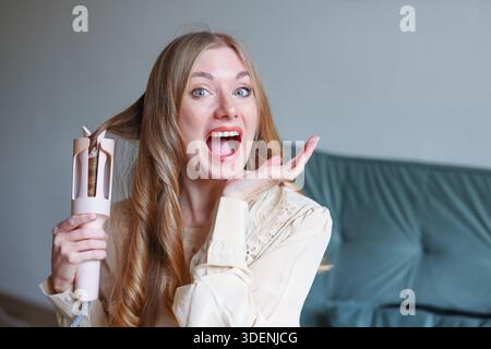 Natürliches Lifestyle-Porträt einer Frau, die lächelt, während sie in angenehmer häuslicher Umgebung die Haare pflegt Stockfoto