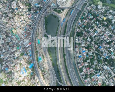Aus der Vogelperspektive sehen Sie komplizierte Autobahnkreuze, die sich durch die urbane Landschaft von Dhaka winden, im Kontrast zu den angrenzenden dicht gepackten Gebäuden, DH Stockfoto