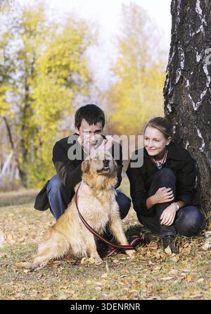 Glückliches junges Paar mit Hund im Herbst Park spielen Stockfoto