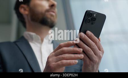 Ruhiger kaukasischer Geschäftsmann aus den 40er Jahren mit Mobiltelefon im Büro mit Blick aus dem Fenster männlicher Spezialist Unternehmer nachdenklicher Geschäftsmann, der Smartphone chattet Stockfoto