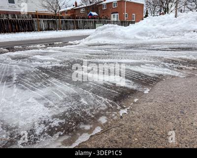 Vereiste Auffahrt. Schnee, gefrorener Untergrund. Rutschige Fahrbahn mit Reifenspuren aus dem Einsatz von Fahrzeugen unter winterlichen Bedingungen, Kanada. Stockfoto