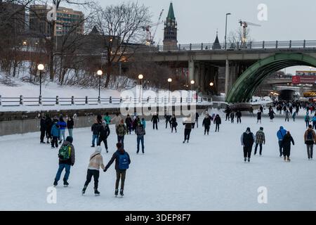 Ottawa, Kanada - 8. Februar 2025: Eislaufbahn am Rideau Canal im Winter. Das Parlamentsgebäude ist abends in der Innenstadt. Stockfoto