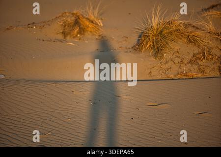 Schatten einer Person, die über warme, gewellte Sanddünen in Vlora, Albanien, geworfen wurde, aufgenommen am 25. August 2025 Stockfoto