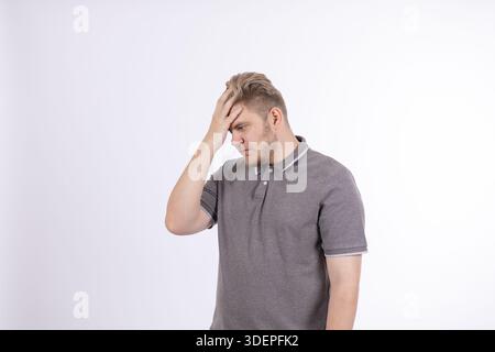 Ein nachdenklicher Mann in einem grauen Poloshirt, der seinen Kopf berührt. Stockfoto