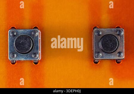 Nahaufnahme von zwei kleinen Drucktasten auf einer orangefarbenen Leiterplatte Stockfoto