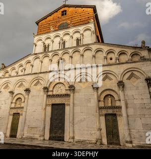 Fachada románica de una iglesia histórica en Lucca,Italia, construida en Mármol claro con arcos decorativos, entlastet escultóricos y puertas de madera. Stockfoto