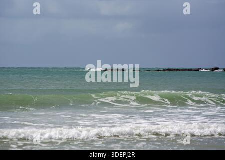 Ruhige Strandszene mit sanften Wellen und felsigem Ausläufer Stockfoto