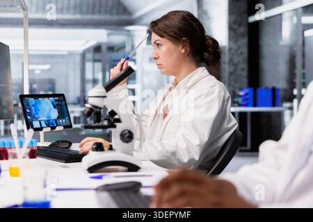 Labortechniker mit Blick auf 3D-Molekülmodellvisualisierung auf Computermonitoren. Frau, die Bioengineering-Software auf dem PC im medizinischen Labor verwendet, DNA-Daten anzeigt, Brainstorming macht Stockfoto