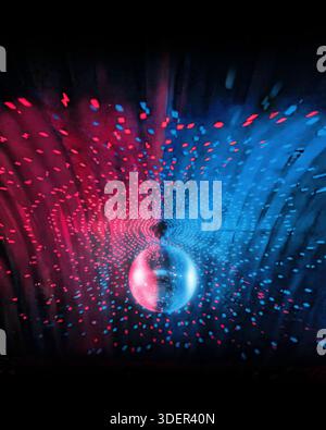 Retro-Discokugel hängt von einer Decke mit roten und blauen Lichtern auf schwarzem Hintergrund. Traumhafte Tanzmusik-Partystimmung aus dem Club. Stockfoto